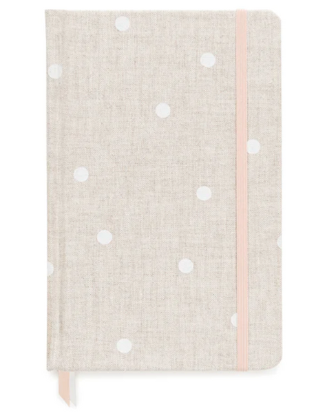 The Sugar Paper Essential Journal, Flax Dot, by Sugar Paper, is a beige, clothbound notebook with white polka dots featuring a pink elastic closure and a ribbon bookmark.