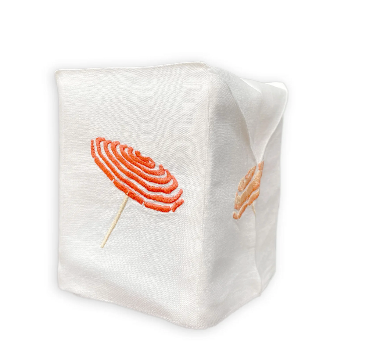 A white Italian linen tissue box cover from the Haute Home Beach Umbrella Bath Collection, featuring embroidered orange lollipops on its sides, is displayed against a plain white background.