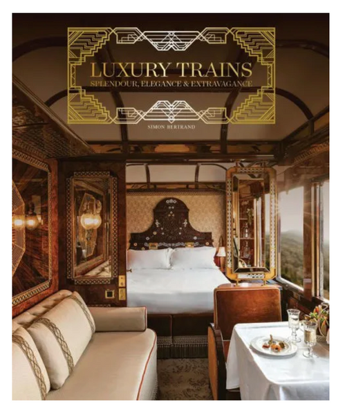Interior of a Common Ground Luxury Trains cabin featuring an elegant bed, plush seating, and a dining table set for a meal, with scenic views visible through the window.