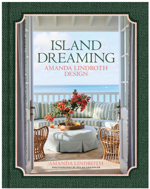 The book cover of "Island Dreaming" by Vendome shows a coastal patio with striped furniture, flowers on the table, and an ocean view through open doors for a tropical feel.