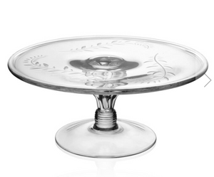 The Jasmine Cake Stand by William Yeoward Crystal features clear glass, an engraved vine floral pattern on the plate, and a sturdy pedestal base.