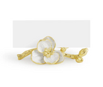 The Michael Aram Orchid Place Card Holder Set features gold and white, handcrafted enamel holders shaped like orchids, adding luxury to your table decor with an elegant blank card behind each decorative bloom.