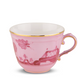 A porcelain teacup from the Ginori 1735 Oriente Italiano Porpora Dinnerware & Decor Collection, featuring a pink hue with gold trim and handle, adorned with a floral pattern and decorative motifs that highlight the refined elegance of Italian craftsmanship.