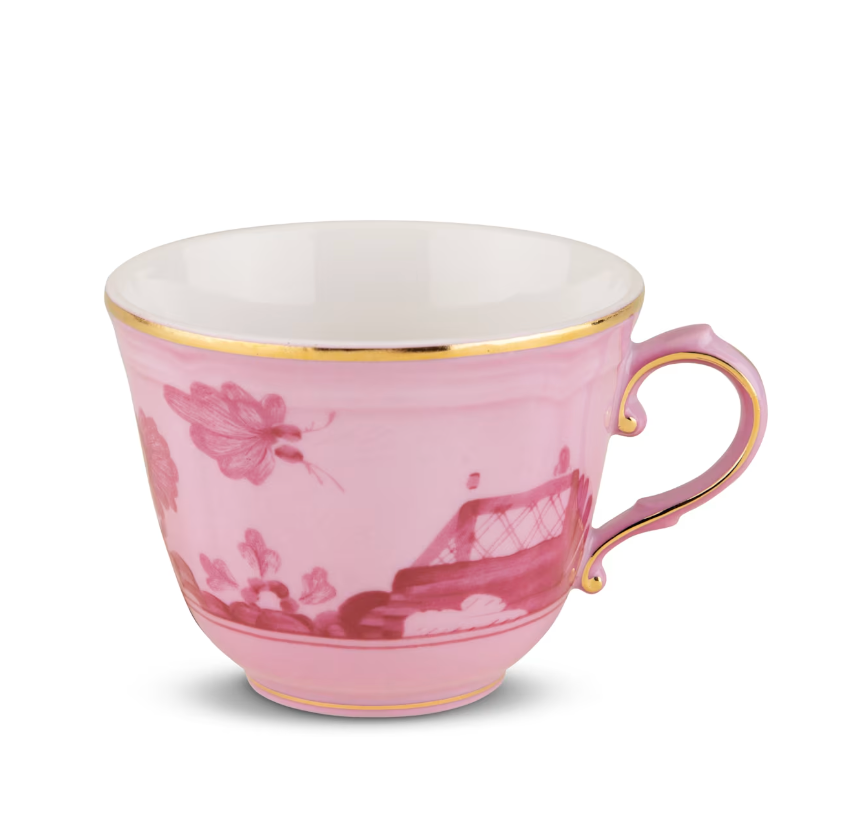 A porcelain teacup from the Ginori 1735 Oriente Italiano Porpora Dinnerware & Decor Collection, featuring a pink hue with gold trim and handle, adorned with a floral pattern and decorative motifs that highlight the refined elegance of Italian craftsmanship.