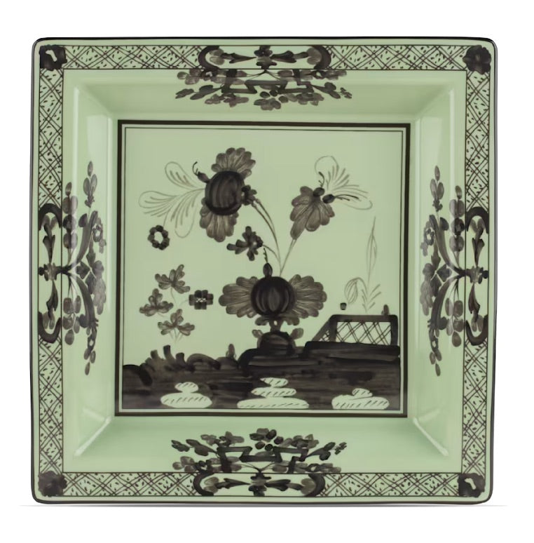 Ginori 1735’s Oriente Italiano Bario Decor Collection features a square porcelain dinner plate adorned with black floral and geometric patterns on a pale green background, showcasing a central botanical design and decorative borders inspired by classic Oriente Italiano motifs.