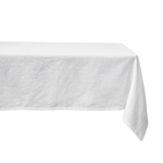 The Juliska Berry Scallop Tablecloth, crafted in Portugal, features elegant white linen that drapes gracefully over the table’s surface and edges.