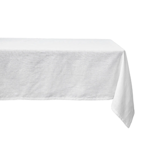 The Juliska Berry Scallop Tablecloth, crafted in Portugal, features elegant white linen that drapes gracefully over the table’s surface and edges.