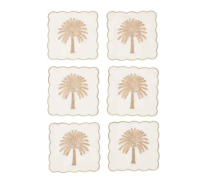The Date Palm Cocktail Napkin Set by Kim Seybert features gold beaded palm trees on white—stylish hostess gifts and a chic match for your coastal décor.