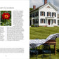 A man spreads a floral tablecloth on an outdoor dining table in front of a white historic house at Clove Brook Farm, the picturesque country retreat featured in A Year at Clove Brook Farm by Common Ground. The left page displays a peony flower and text about a peony-themed luncheon.