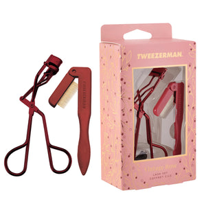 A red lash curler and comb are shown beside a pink and gold floral box labeled “Tweezerman Vintage Rose Lash Set,” part of Tweezerman’s Vintage Rose Gift Sets.