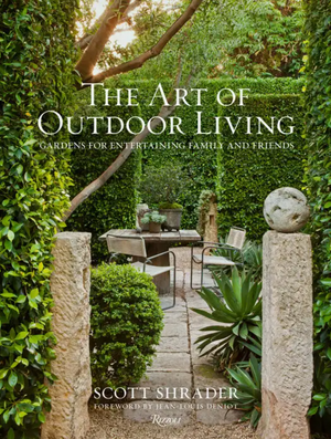 Book cover features a lush formal garden with manicured hedges, stone pillars, elegant patio furniture, and classic statues—ideal inspiration for outdoor entertaining. The text reads “The Art of Outdoor Living” by Scott Shrader, published by Rizzoli—a sophisticated coffee table book that celebrates exceptional garden design.