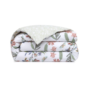 The Eze Bedding Collection by Yves Delorme features a folded organic cotton comforter with a floral and butterfly print on white, plus a contrasting light green patterned reverse.