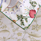Close-up of a Botanic Bedding Collection pillow sham in organic cotton sateen with colorful botanical embroidery, resting on a flat sheet with a muted green floral pattern.