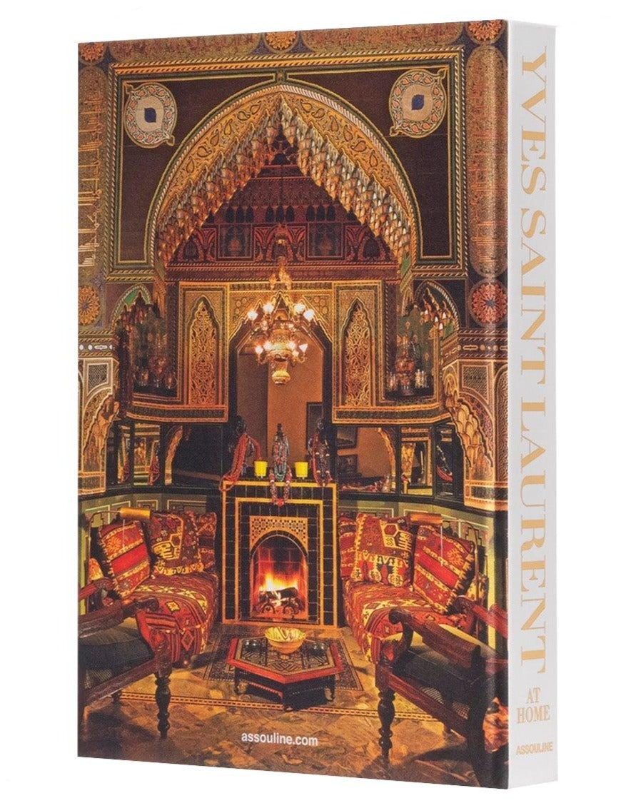 The book "Yves Saint Laurent at Home" by Assouline, features a cover with an ornately decorated room in warm tones and intricate patterns, showcasing the exquisite interior design mastery of Jacques Grange.