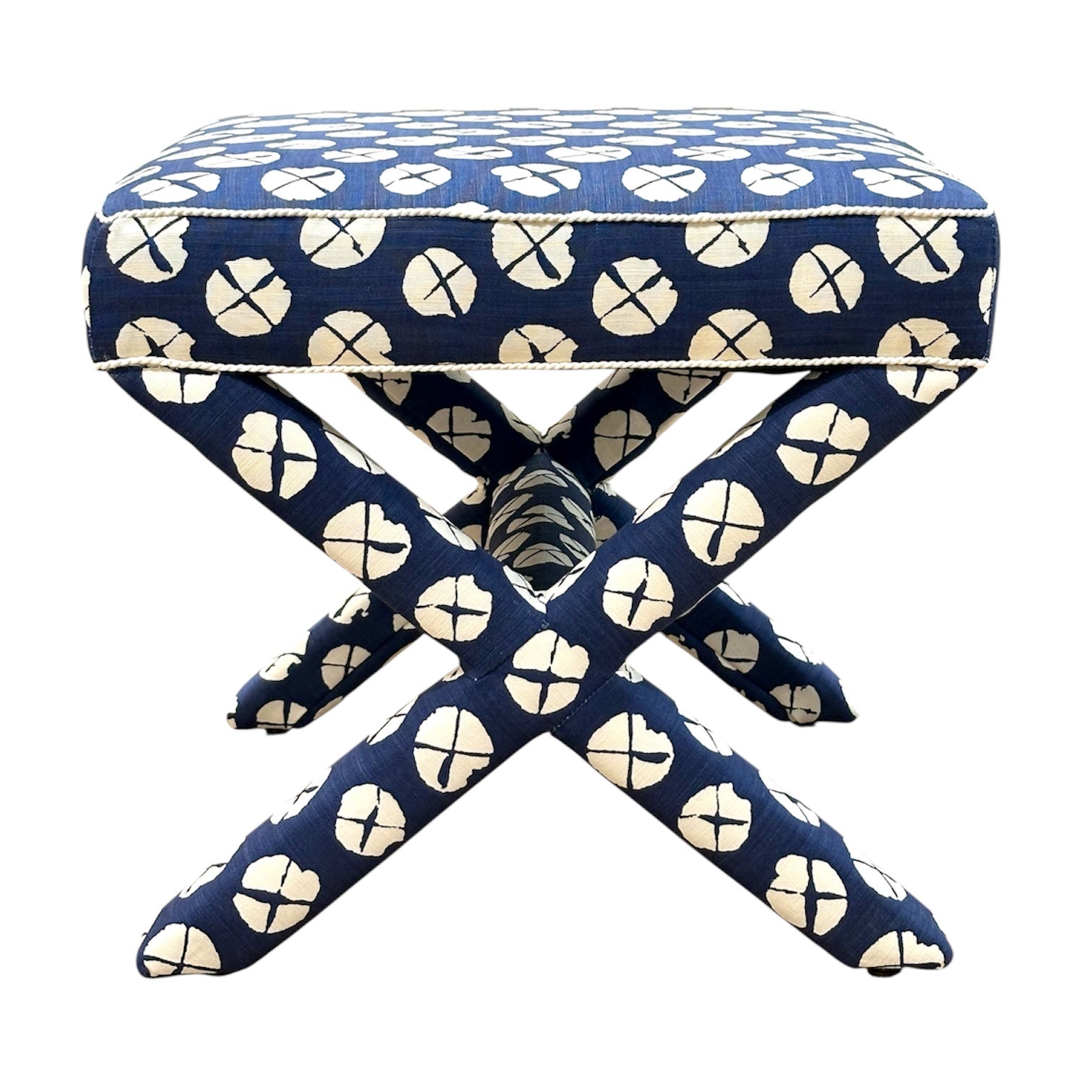 The Lee Industries X Ottoman features a square upholstered top with a blue and white circular pattern, crossed legs, and decorative edge trim—making it the perfect accent seat for any room.