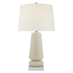 The Parisienne Medium Lamp in Coconut Porcelain by Visual Comfort features a geometric base with a reactive ceramic glaze and a large white lampshade, set on a small square metal platform.