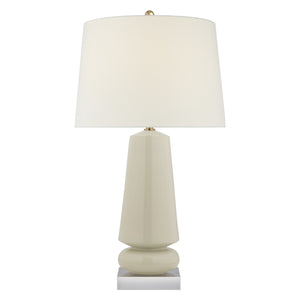 The Parisienne Medium Lamp in Coconut Porcelain by Visual Comfort features a geometric base with a reactive ceramic glaze and a large white lampshade, set on a small square metal platform.