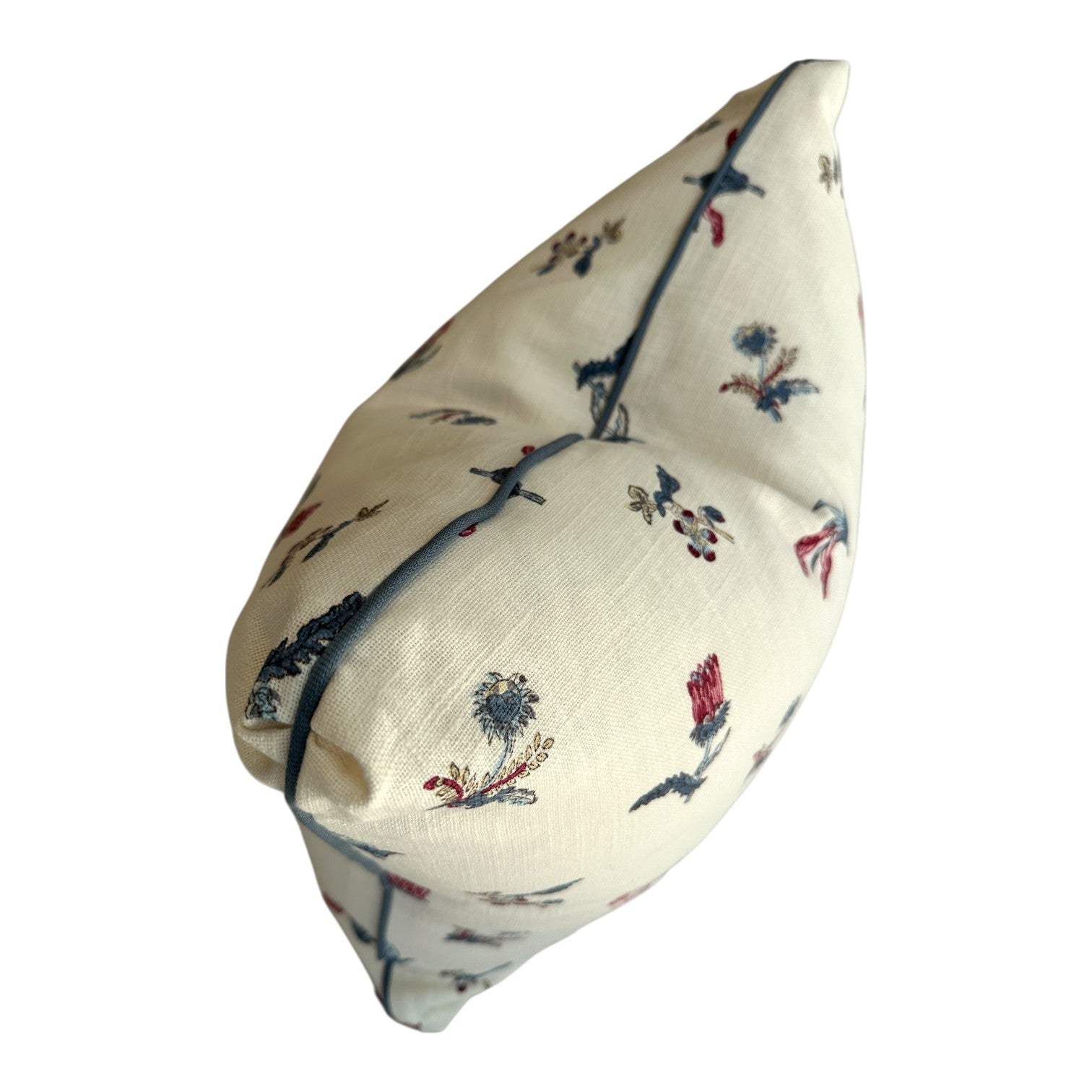 The Flora Calico Pillow by Hive Custom Pillows is a cream-colored 22x22 pillow with blue piping and a floral and bird design in blue, red, and gray, pictured from the side.