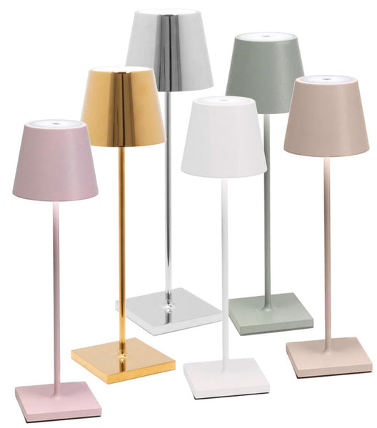 A set of six modern, dimmable Zafferano Poldina Pro Cordless Lamps by Zafferano America features sleek, metallic bases and simple, conical shades in various colors, including gold, silver, pink, beige, white, and green. Each lamp offers cordless illumination with a rechargeable battery for ultimate convenience.