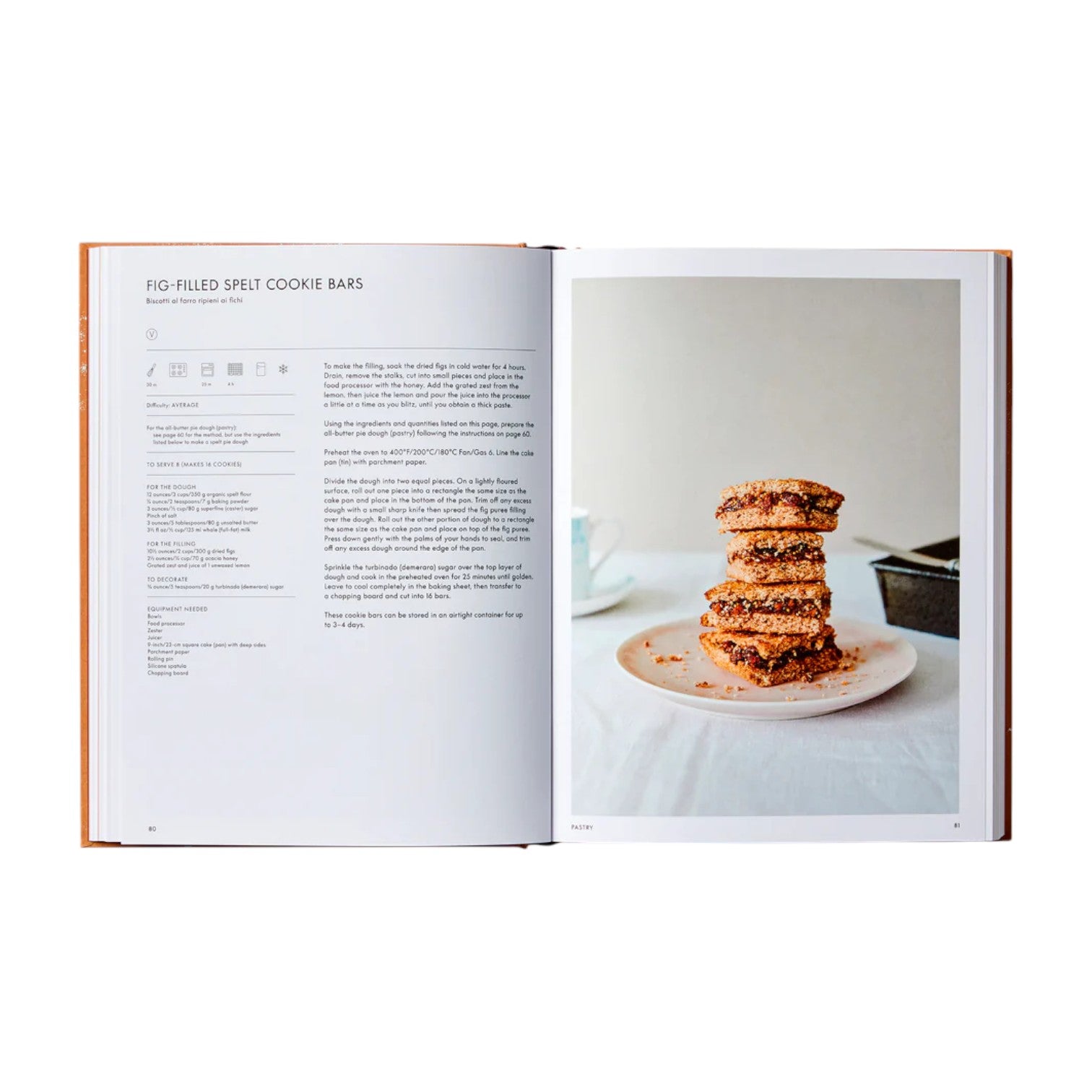 An open copy of The Italian Bakery by Phaidon shows a fig-filled spelt cookie bar recipe on the left and a photo of stacked bars on a white plate on the right.