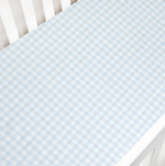 A white crib with a Gooselings Picnic Gingham Blue Crib Sheet, OEKO-TEX certified and extra soft, fitted over the mattress.
