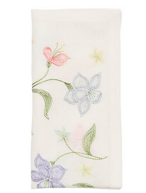 The Vista Napkin Set by Kim Seybert features folded white napkins with hand-embroidered pastel flowers and green stems—an elegant choice for garden parties or bridal luncheons.