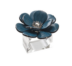 The Begonia Napkin Ring by Kim Seybert features a decorative blue and black floral design with silver accents, reminiscent of an intricate sculpture, mounted on a clear rectangular base.
