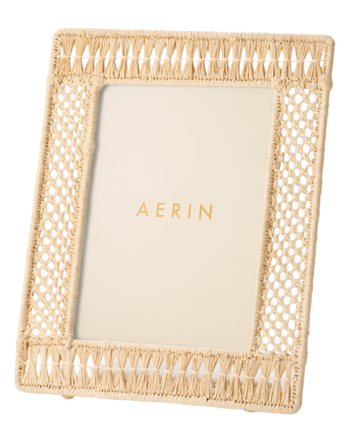 AERIN Raffia Frame by Aerin features a beige hand-woven frame with a white insert, showcasing "AERIN" in gold letters for an organic appeal.