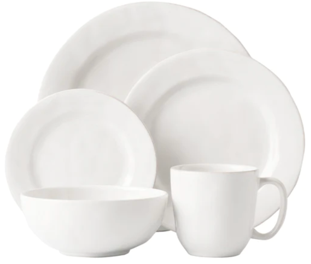 The Juliska Puro Whitewash Dinnerware Collection features two plates, a bowl, and a mug in classic white—ideal for serving teatime treats or savory tapas, elegantly displayed against a minimalist background.