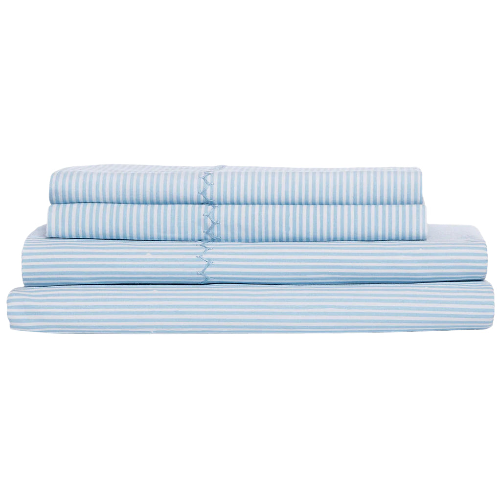 The Nandi Light Indigo Sheet Set by John Robshaw, made in India from organic cotton, features blue and white stripes and is neatly stacked against a white background.