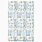 The Mihana Mist Bedding Collection by John Robshaw features folded organic cotton fabric with a white background, adorned with blue flowers and green leaves for botanical harmony.