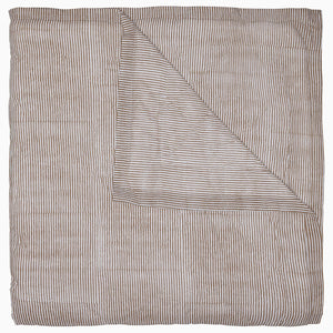 The John Robshaw Nandi Coffee Quilt is a soft cotton voile quilt featuring thin, horizontal brown and white stripes. It's folded to show its reversible design with the same stripe pattern on both sides.