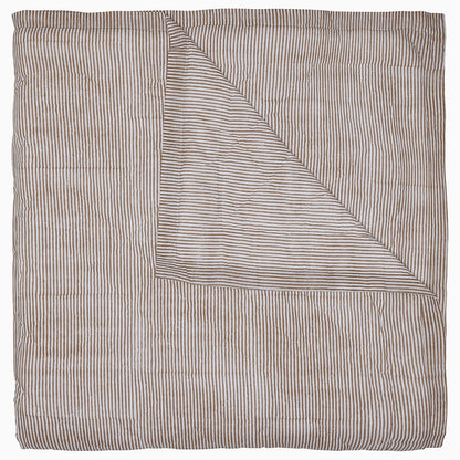 The John Robshaw Nandi Coffee Quilt is a soft cotton voile quilt featuring thin, horizontal brown and white stripes. It's folded to show its reversible design with the same stripe pattern on both sides.