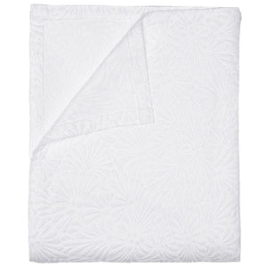The Meera Bedding Collection by John Robshaw features a white textured bedspread with a subtle floral design, artfully shown folded with one corner turned to reveal the reverse—expertly crafted as a woven cotton coverlet that highlights exquisite Portuguese textile artistry.
