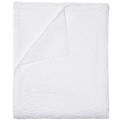 The Meera Bedding Collection by John Robshaw features a white textured bedspread with a subtle floral design, artfully shown folded with one corner turned to reveal the reverse—expertly crafted as a woven cotton coverlet that highlights exquisite Portuguese textile artistry.