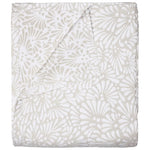 The Meera Sand Bedding Collection by John Robshaw features a folded beige and white jacquard coverlet with a floral pattern, one corner turned to reveal the reverse—an elegant bedding choice for any room.