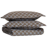 A folded Kaarik Coffee Duvet by John Robshaw, featuring a brown and blue floral pattern in organic cotton, with two matching pillowcases stacked on top.