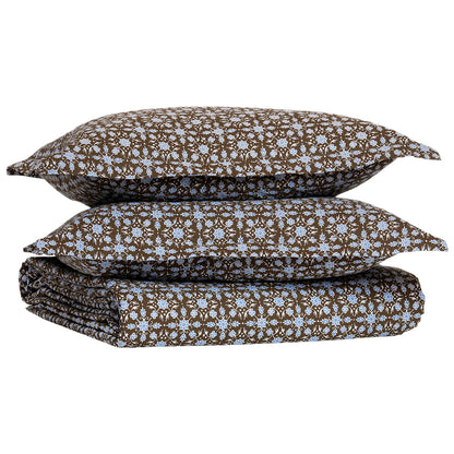 A folded Kaarik Coffee Duvet by John Robshaw, featuring a brown and blue floral pattern in organic cotton, with two matching pillowcases stacked on top.