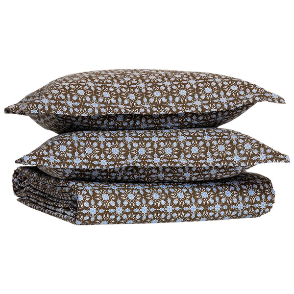 Two brown pillows with a white and light blue floral pattern rest atop a matching folded John Robshaw Kaarik Coffee Duvet, crafted from soft, organic cotton.