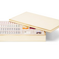 The Aerin Luxe Shagreen Mahjong Set in cream features a luxurious box with a partially open lid, revealing neatly arranged engraved tiles, dice, and playing pieces inside.