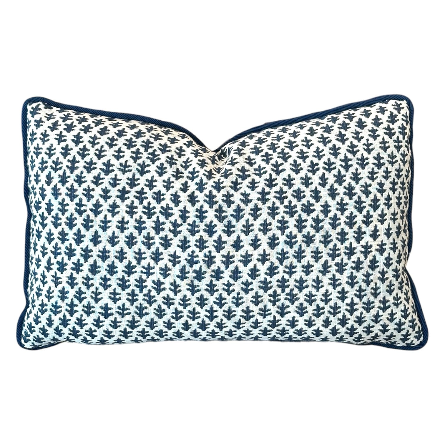 The Burma White Indigo Outdoor Lumbar Pillow by Associated Design features a navy blue leaf pattern on a white background with navy piping, adding stylish quality craftsmanship to any space.