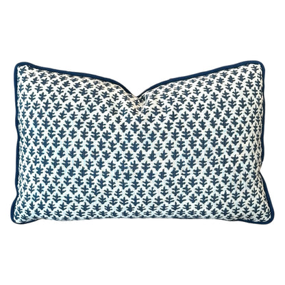 The Burma White Indigo Outdoor Lumbar Pillow by Associated Design features a navy blue leaf pattern on a white background with navy piping, adding stylish quality craftsmanship to any space.