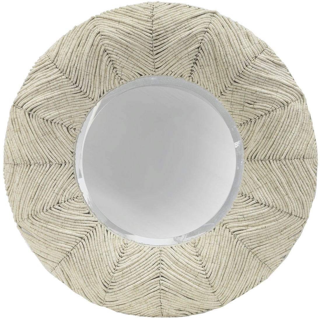 The Sabine Coco Mirror by PALECEK features a round beveled mirror with a woven beige frame displaying a geometric pattern adorned with coconut shell beads.