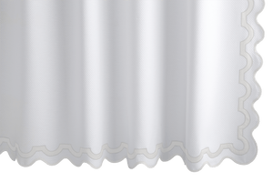 The Matouk Mirasol Shower Curtain in Bone showcases a scalloped edge and a subtle textured pattern, similar to Diamond Pique.