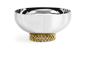 The Love Knot Small Bowl by Michael Aram features a reflective silver finish and rests on a textured, gold-toned woven base, symbolizing unity and togetherness.