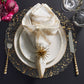 A formal table setting features the Kim Seybert Luna Napkin Set, starburst napkin ring, gold-accented plates, silverware, glassware, and flowers on a dark surface—perfect for an elegant bridal shower.