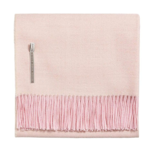 The Alicia Adams Alpaca Classic Throw Herringbone Light Pink is a folded, pink blanket with fringe on the bottom edge. It features a woven label near the top left corner and makes a charming anniversary gift.