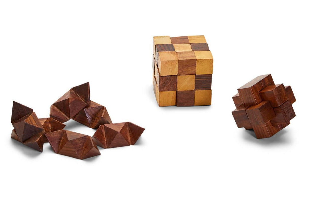 The Turf Club Wood Crafted Puzzles by Two's Company features three acacia wood puzzles: a solved cube, a star-shaped piece, and a disassembled set on a white background, each offering its own brain teaser challenge for your visual-spatial skills.
