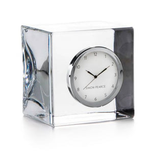 The Woodbury Clock by Simon Pearce features a square glass design with a round white face and silver rim, displaying 10:11—a timeless gift for any occasion.