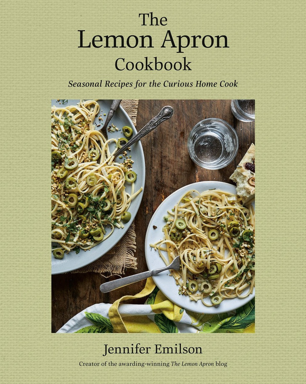 Cover of "The Lemon Apron Cookbook" by Jennifer Emilson, featuring a title and subtitle with two plates of pasta. The book is described as having rustic recipes for the curious home cook, perfect for those who love comfort home cooking with seasonal ingredients. The Lemon Apron Cookbook by Common Ground offers an array of delightful, seasonally inspired dishes that bring warmth and comfort to your table.